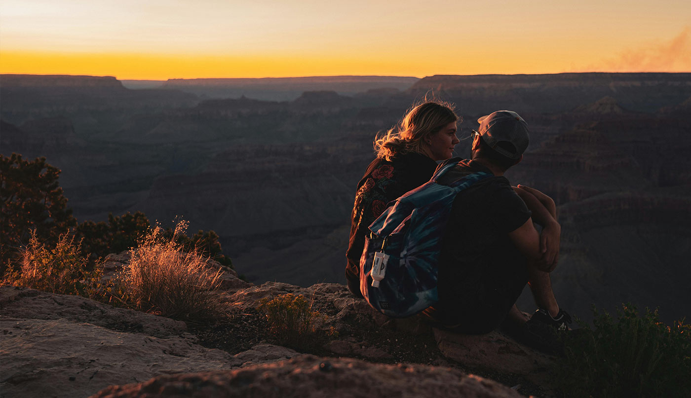Two people sitting on a cliff talking about natural therapy