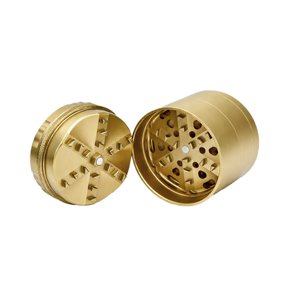 Gold metal grinder with open top and side on a white background